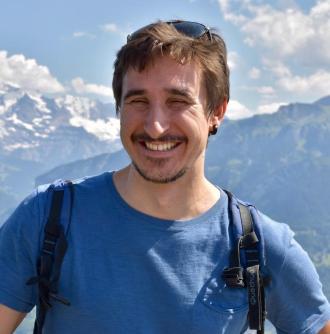 Stefano, jeune homme souriant au cheveux brun et barbe naissante