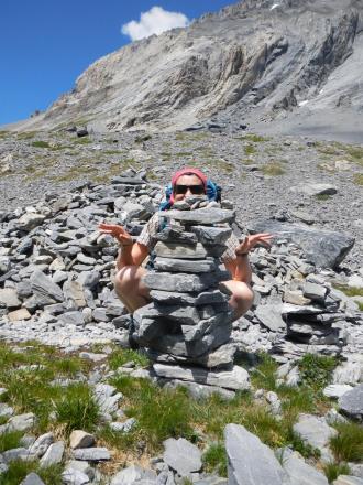 Une personne se cache derrière une pile de pierres en montagne